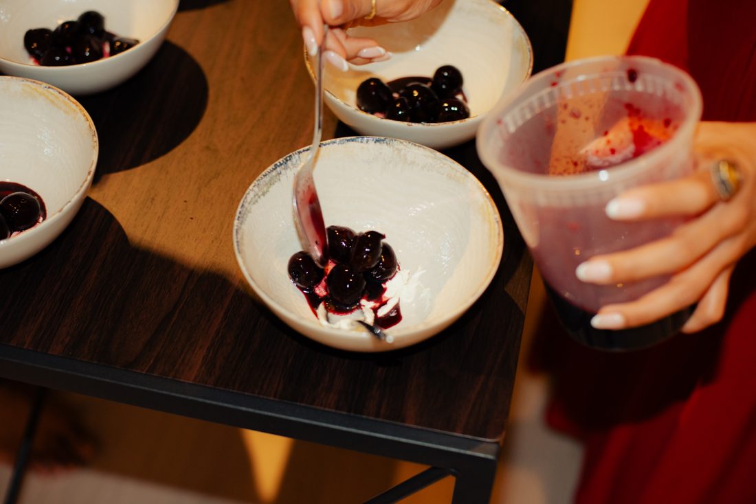 Spooning cream over the cherry dessert